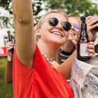 Drei Studierende feiern mit Bierflaschen auf dem Campus