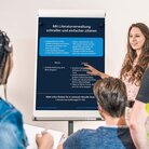 Three Students listening to a girl on a flipchart