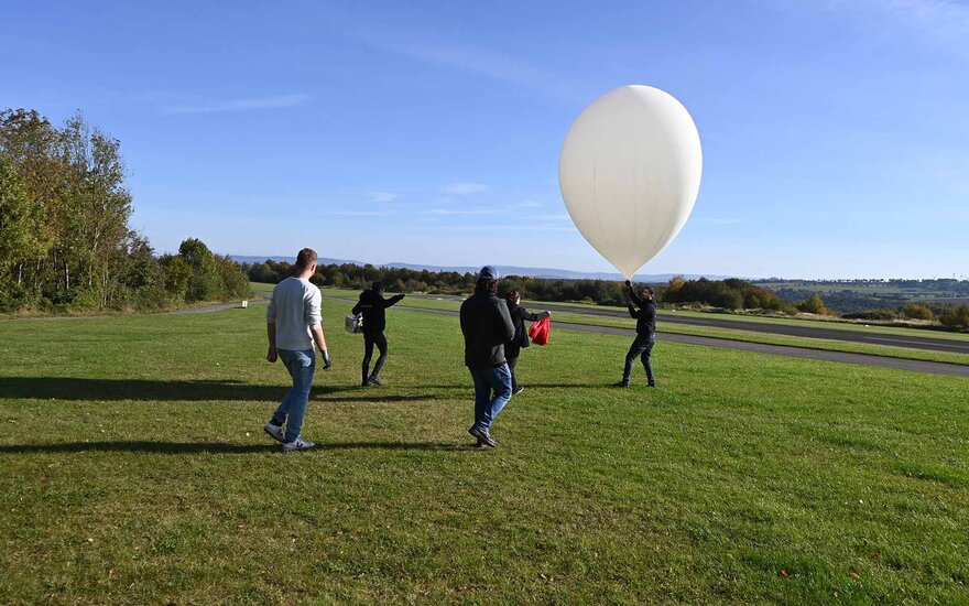 Das Forschendenteam bringt den Stratosphärenballon auf einer großen Wiese in Position