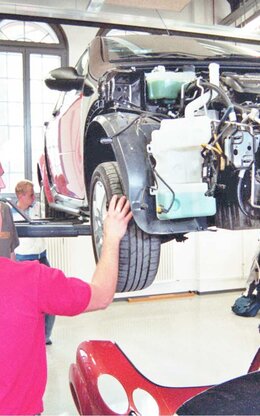 Menschen stehen vor einem KFZ Verbrennungsmotor