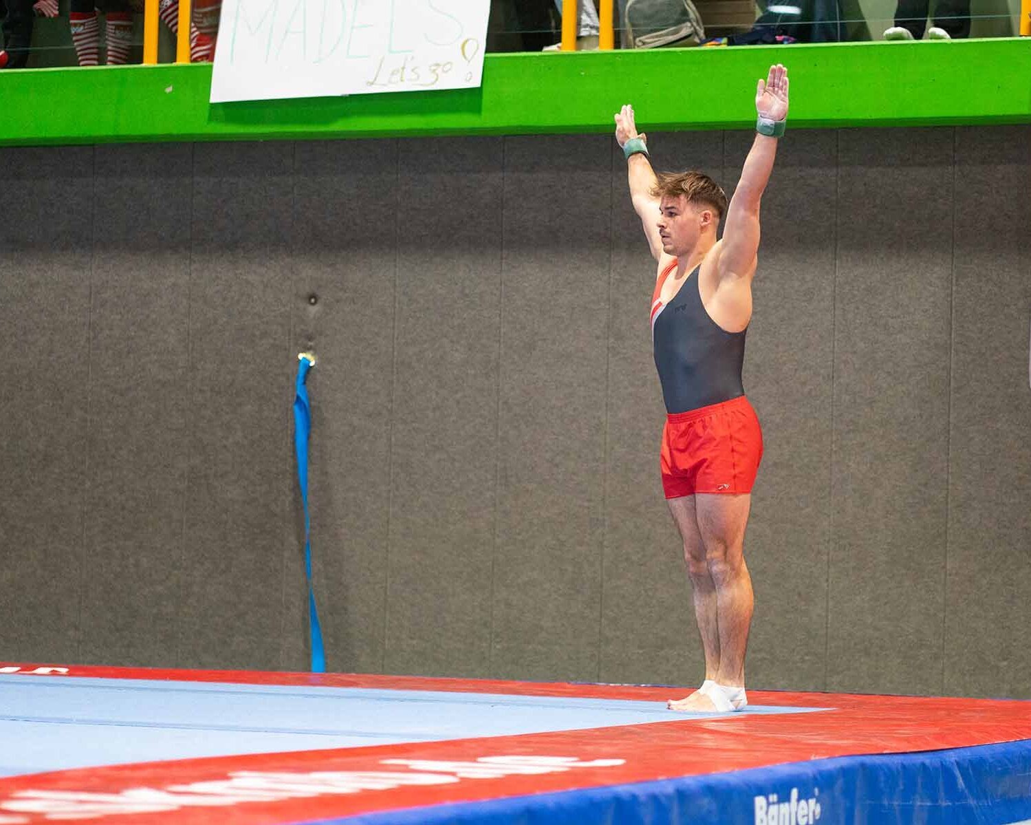 Maximilian in Startposition mit ausgestreckten Armen auf der Matte vor der Tribüne