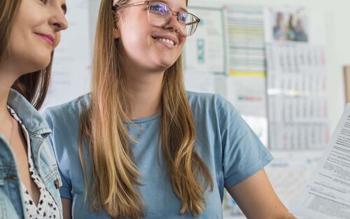 Zwei Studentinnen an der Theke des Dekanat WR