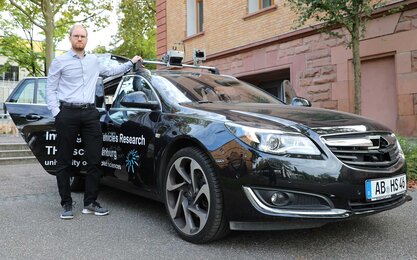 Ein junger Mann steht am Forschungsfahrzeug der TH Aschaffenburg.