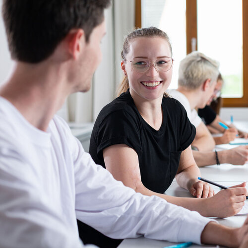 Lachende Studentin mit Lerngruppe in einem Seminarraum