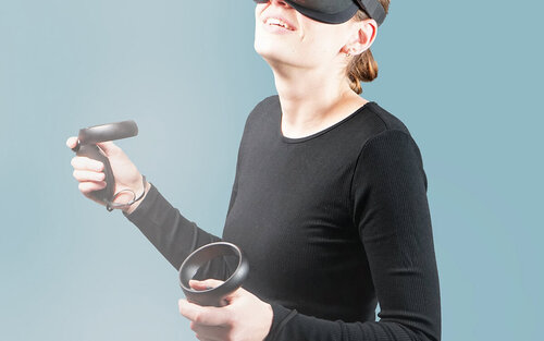 Eine Frau mit VR-Brille und Joysticks.