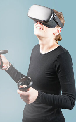 Eine Frau mit VR-Brille und Joysticks.