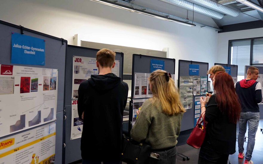 Eine Gruppe von Schülerinnen und Schülern schaut sich die Posterausstellung an.