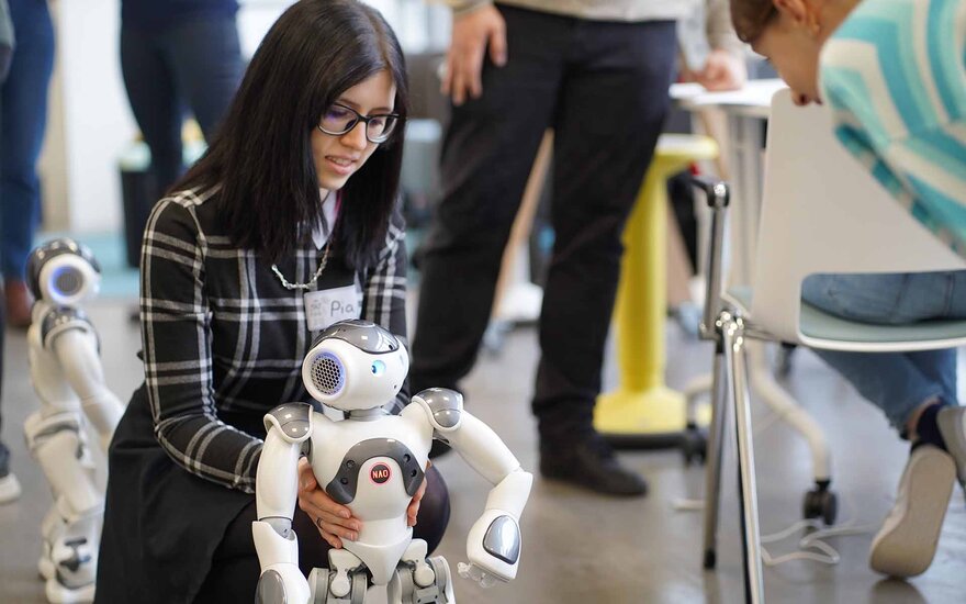 Ein Mädchen spielt mit einem Mini Roboter.