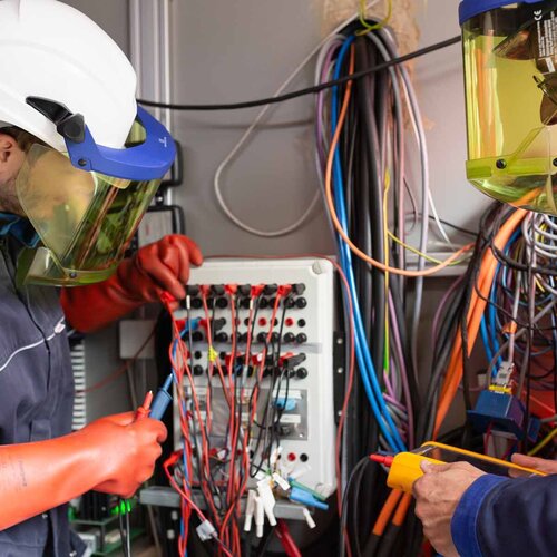 Zwei Männer in Schutzkleidung arbeiten an der Elektrik.