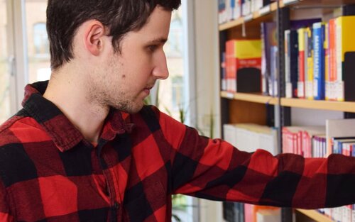 Student greift in Bücherregal in Bibliothek 