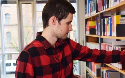 Student greift in Bücherregal in Bibliothek 