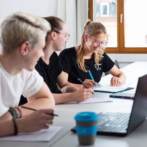 Mehrere Studierende während einer Gruppenarbeit mit Laptop und TH AB To-Go Becher.