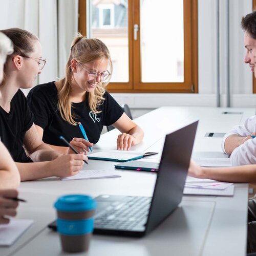 Mehrere Studierende während einer Gruppenarbeit mit Laptop und TH AB To-Go Becher.