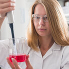 Eine Studentin mit einer Pipette und einem Becherglas mit Flüssigkeit in einem Labor an der TH Aschaffenburg.