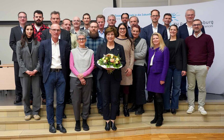 Gruppenfoto des Hochschulrats mit der Präsidentin mit Blumenstrauß in der Hand