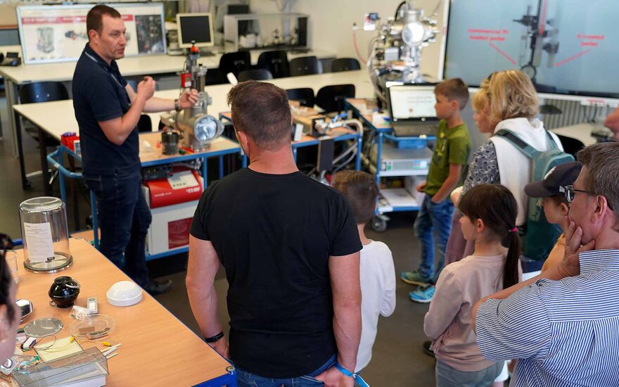 Angehöriger der Fakultät Ingenieurwissenschaften führt Besuchern im Labor eine Maschine vor.