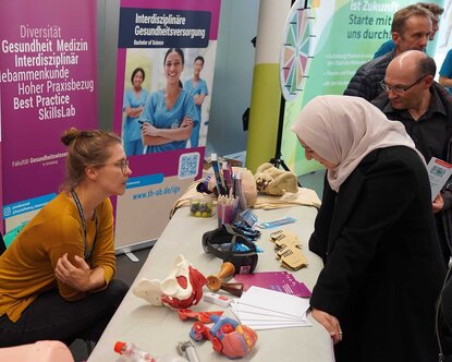 Eine Frau mit Kopftuch informiert sich am Stand der Fakultät Gesundheit 