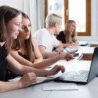 Vier Studierende mit Laptops in Seminarraum von der Seite