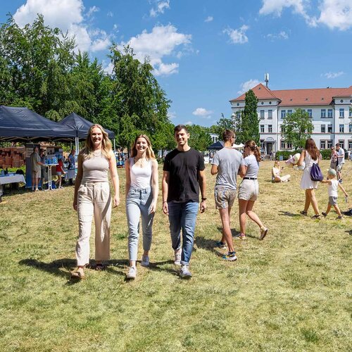 Besucherinnen und Besucher beim Open Campus an der Technischen Hochschule Aschaffenburg auf der Campuswiese mit Infoständen und dem weißen Gebäude der Fakultät Wirtschaft und Recht im Hintergrund