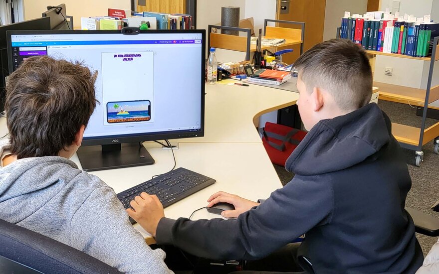 Zwei Jungs sitzen am Boys day in der Bibiliothek an einem Computer.