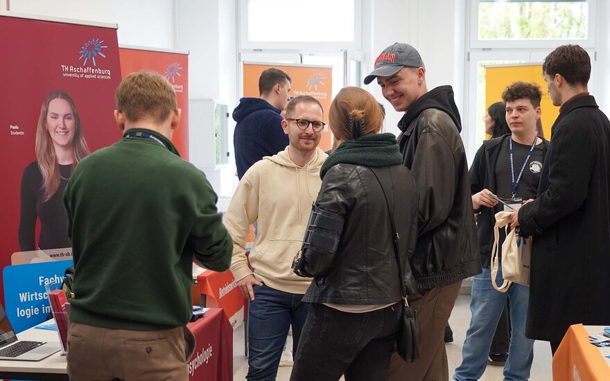 Mehrere Personen informieren sich an einem Stand über die Studienangebote.