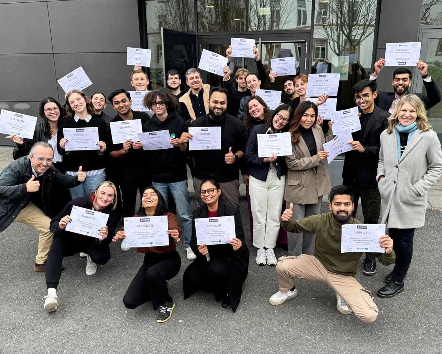 Gruppenfoto der Mercuri-Studierenden auf dem Campus mit Zertifikaten in der Hand