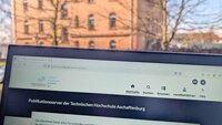 Bildschirm mit Website zum Publikationsserver vor Fenster mit rotem Backsteingebäude der TH