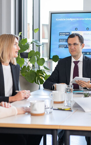 Fünf Personen sitzen an einem Meeting-Tisch 