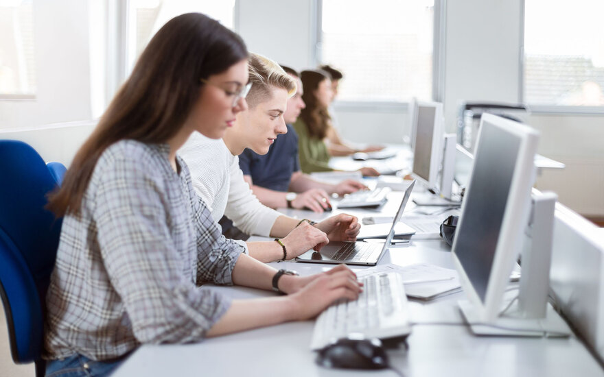 Studierende arbeiten an PCs in einem Vorlesungssaal.