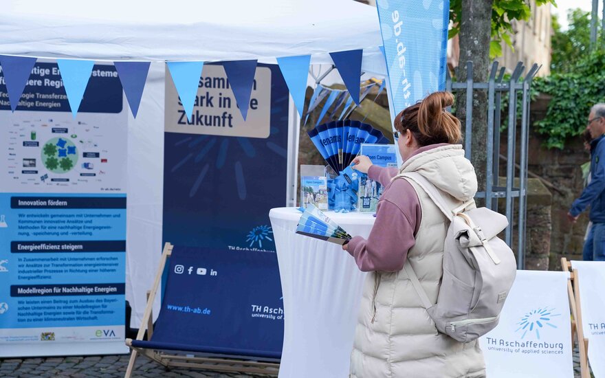 Eine Frau nimmt sich Werbemitel von unserem Stand der TH AB beim Citylauf.