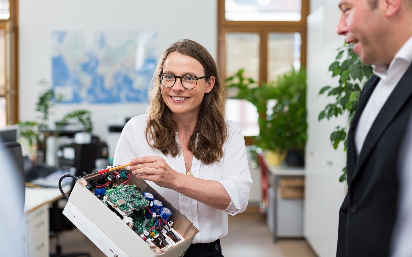 Frau zeigt Mann ein Forschungsprojekt. Im Hintergrund ist ein Büro.