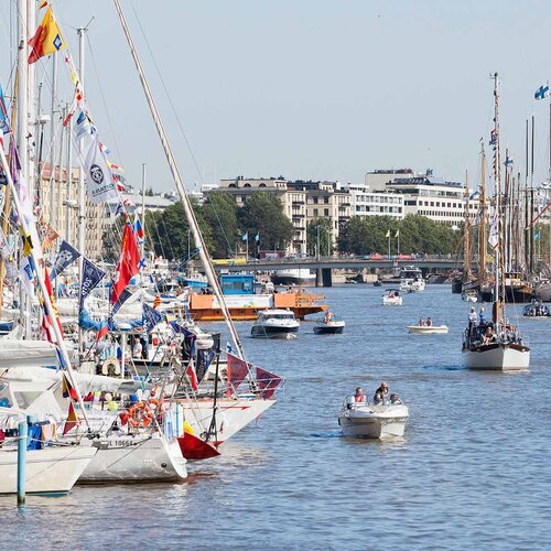 Segelboote auf dem Wasser an einem Hafen. Im Hintergrund ist eine Stadt. 