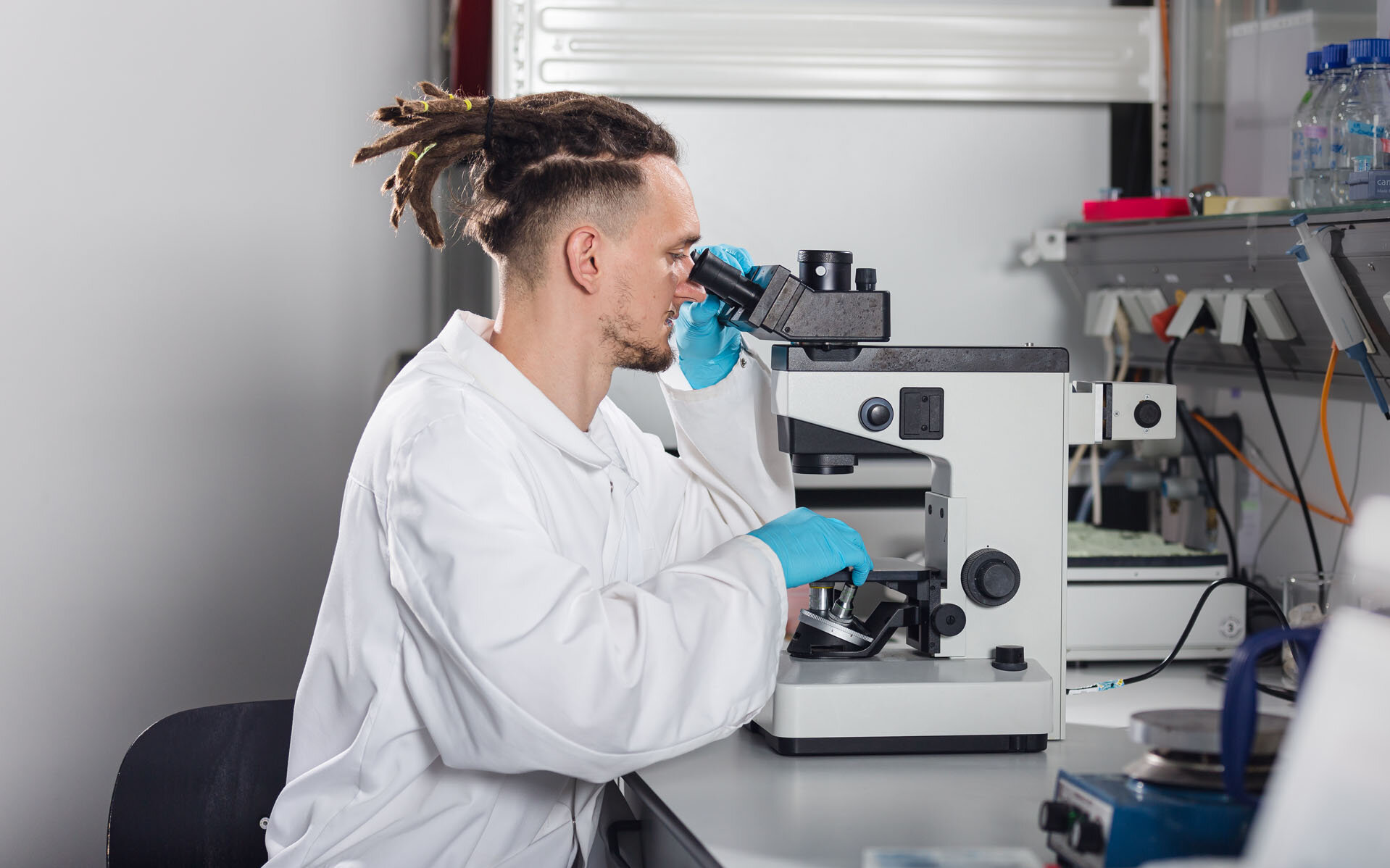 A BioMEMS Lab employee looks through a microscope.