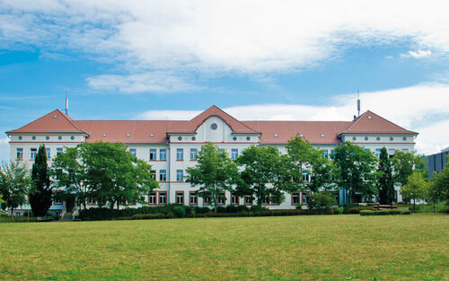 Campus-Wiese und Gebäude 20 am Campus 1 Hochschulgebäude der Technischen Hochschule Aschaffenburg, umgeben von Grünanlagen an einem sonnigen Tag.