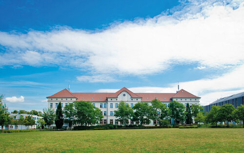 Campus-Wiese und Gebäude 20 am Campus 1 Hochschulgebäude der Technischen Hochschule Aschaffenburg, umgeben von Grünanlagen an einem sonnigen Tag.