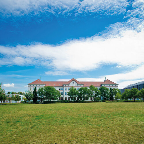 Campus-Wiese und Gebäude 20 am Campus 1 Hochschulgebäude der Technischen Hochschule Aschaffenburg, umgeben von Grünanlagen an einem sonnigen Tag.