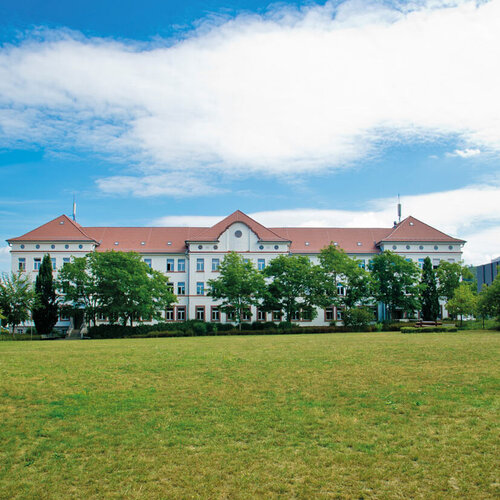 Campus-Wiese und Gebäude 20 am Campus 1 Hochschulgebäude der Technischen Hochschule Aschaffenburg, umgeben von Grünanlagen an einem sonnigen Tag.