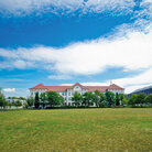 Campus-Wiese und Gebäude 20 am Campus 1 Hochschulgebäude der Technischen Hochschule Aschaffenburg, umgeben von Grünanlagen an einem sonnigen Tag.