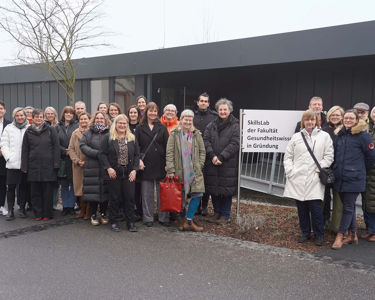 Gruppenfoto der Teilnehmenden vor dem Schild und Container der Fakultät Gesundheitswissenschaften.