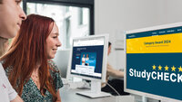 Eine Studentin und ein Student sitzen vor einem Bildschirm, auf dem die Seite von Studycheck mit dem Category Award zu sehen ist.