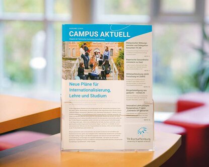 Einige Exemplare des aktuellen Hochschulmagazin "Campus aktuell" in einem transparenten Zeitschriftenständer vor einem Fenstser