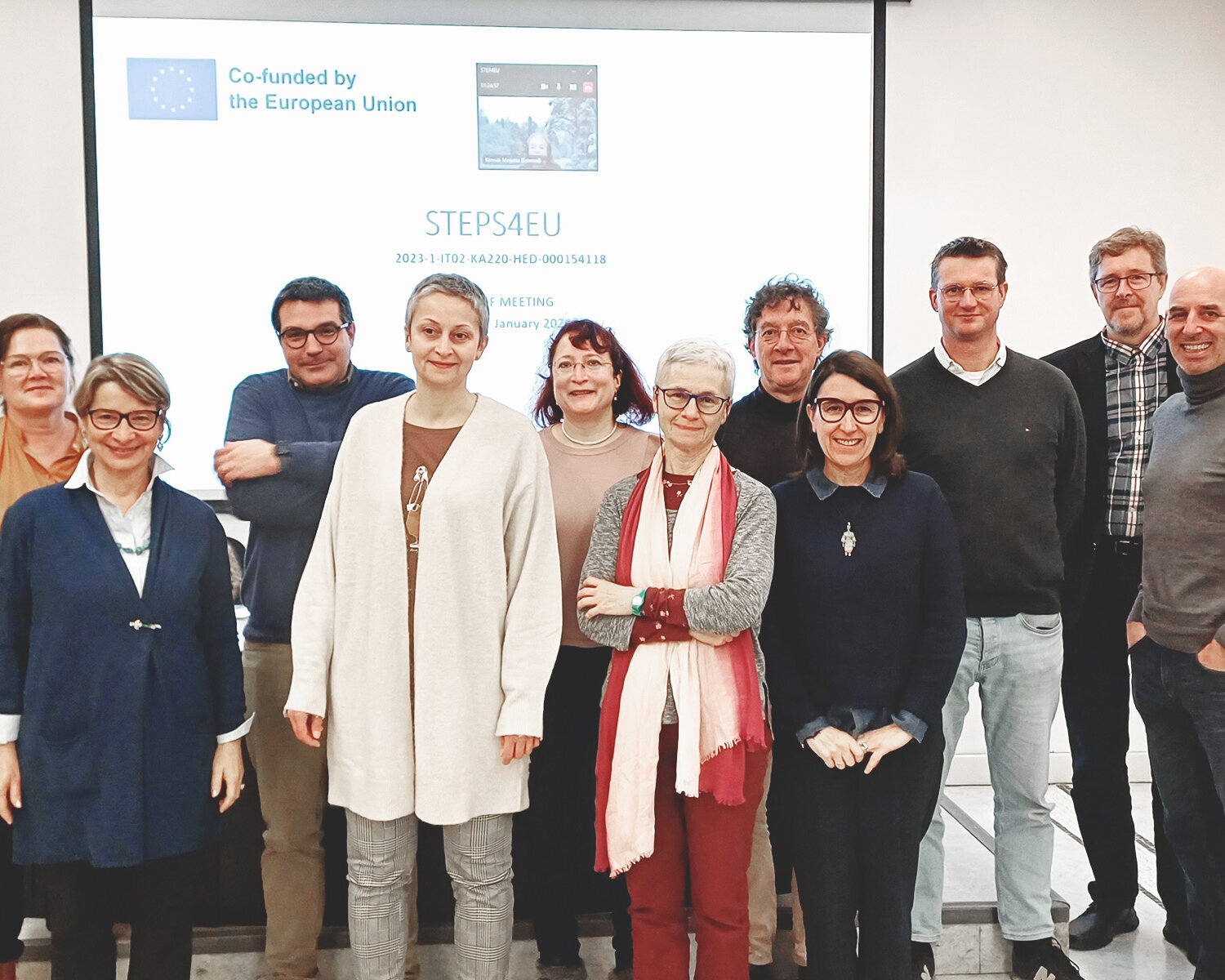 Gruppe von 11 Menschen vor einer weißen Leinwand mit der Aufschrift "STEPS4EU".