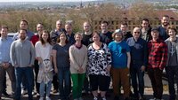 Gruppenfoto mit allen Teammitglieder unter freiem Himmel mit dem Stadtpanorama von Aschaffenburg im Hintergrund