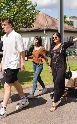 Mehrere Studierende der Studentenvertretung mit Bollerwagen auf dem Campus 1