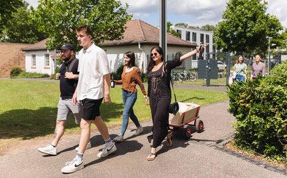 Mehrere Studierende der Studentenvertretung mit Bollerwagen auf dem Campus 1