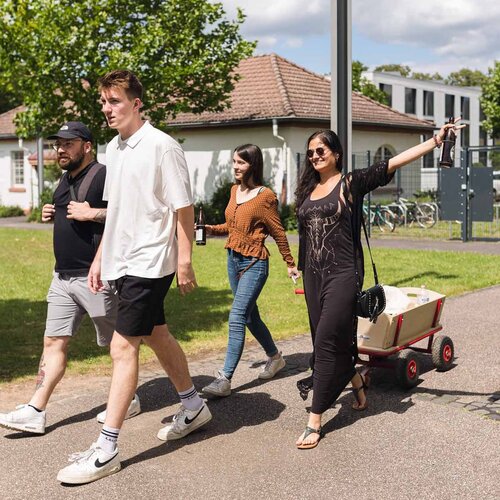 Mehrere Studierende der Studentenvertretung mit Bollerwagen auf dem Campus 1