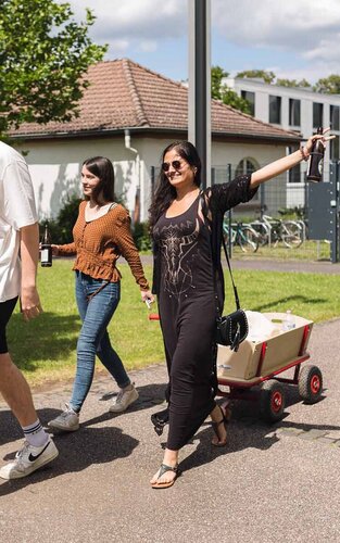 Mehrere Studierende der Studentenvertretung mit Bollerwagen auf dem Campus 1