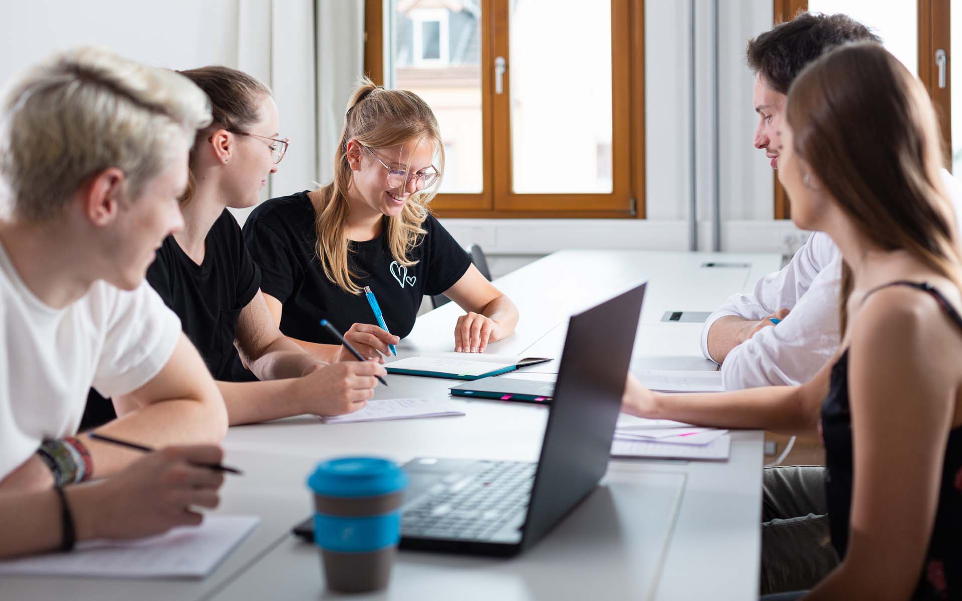 Mehrere Studierende während einer Gruppenarbeit mit Laptop und TH AB To-Go Becher.