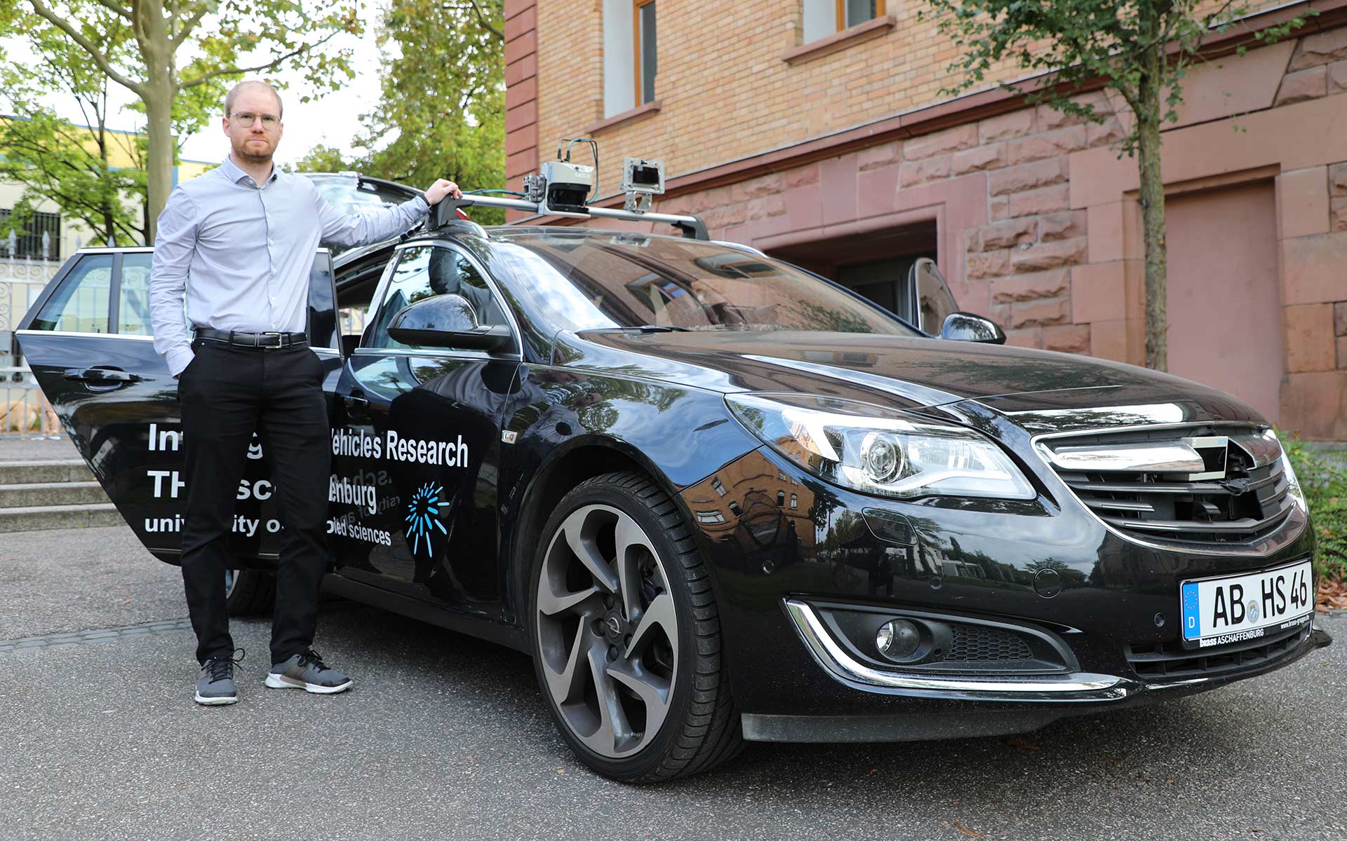 Ein junger Mann steht am Forschungsfahrzeug der TH Aschaffenburg.