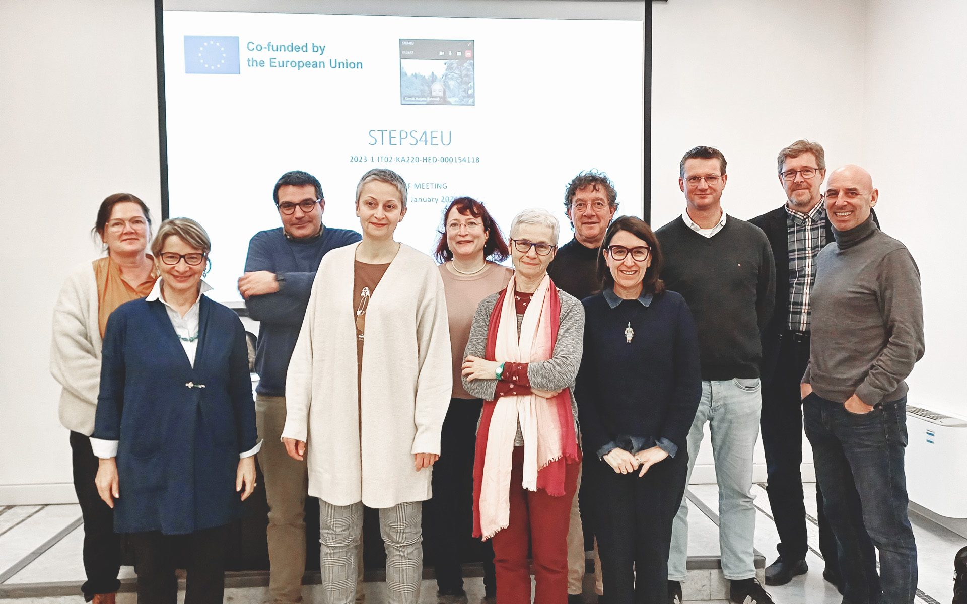 Gruppe von 11 Menschen vor einer weißen Leinwand mit der Aufschrift "STEPS4EU".